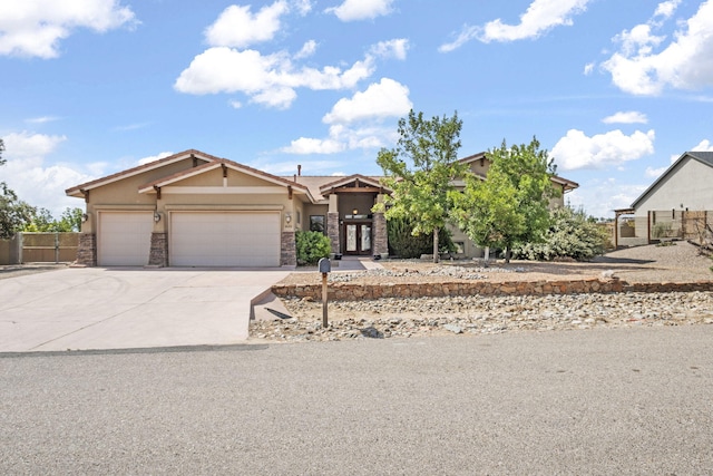 2632 Globe Ct NE, Rio Rancho, NM 87124 - view of front facade with stucco siding, an attached garage, driveway, stone siding, and french doors