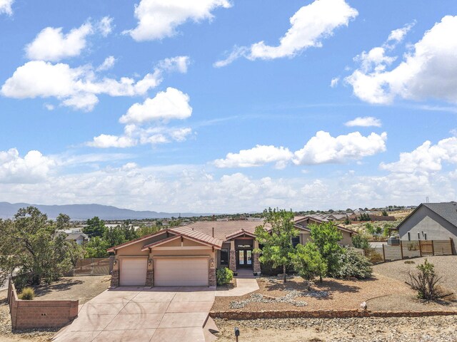 2632 Globe Ct NE, Rio Rancho, NM 87124 - view of front of home featuring concrete driveway, an attached garage, stone siding, stucco siding, and a mountain view