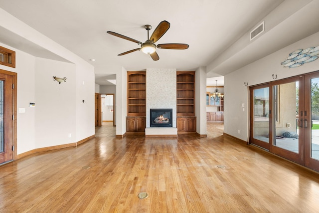 2632 Globe Ct NE, Rio Rancho, NM 87124 - unfurnished living room with built in shelves, a large fireplace, light wood finished floors, french doors, and a ceiling fan
