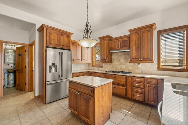 2632 Globe Ct NE, Rio Rancho, NM 87124 - kitchen featuring appliances with stainless steel finishes, a kitchen island, backsplash, light stone counters, and decorative light fixtures