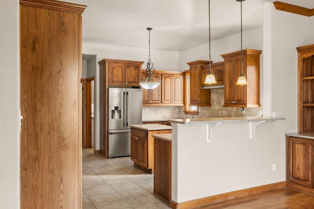 2632 Globe Ct NE, Rio Rancho, NM 87124 - kitchen with stainless steel refrigerator with ice dispenser, backsplash, a breakfast bar, brown cabinetry, and light stone countertops
