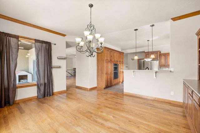 2632 Globe Ct NE, Rio Rancho, NM 87124 - kitchen featuring stainless steel appliances, a peninsula, light wood-style flooring, brown cabinets, and a chandelier