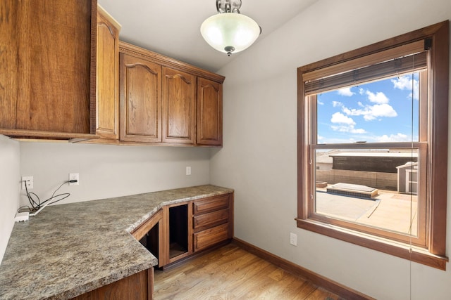 2632 Globe Ct NE, Rio Rancho, NM 87124 - kitchen with light wood finished floors, lofted ceiling, brown cabinetry, and pendant lighting