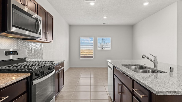 5623 Sagan Loop SE, Albuquerque, NM 87106 - kitchen featuring stainless steel appliances, dark brown cabinetry, light stone counters, backsplash, and a textured ceiling