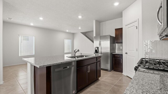 5623 Sagan Loop SE, Albuquerque, NM 87106 - kitchen with stainless steel appliances, light tile patterned floors, an island with sink, tasteful backsplash, and light stone countertops