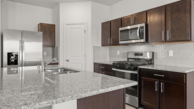 5623 Sagan Loop SE, Albuquerque, NM 87106 - kitchen with appliances with stainless steel finishes, dark brown cabinetry, light stone countertops, and backsplash