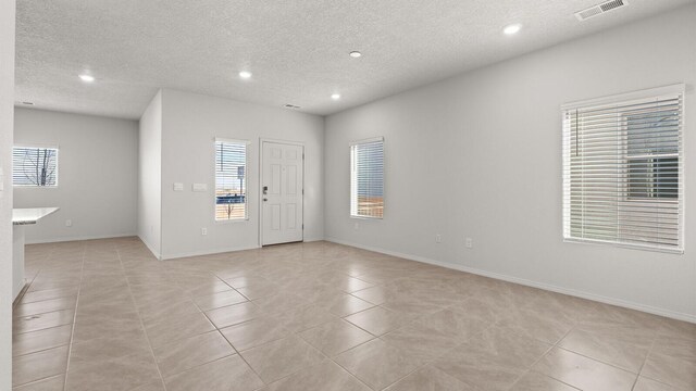 5623 Sagan Loop SE, Albuquerque, NM 87106 - spare room featuring light tile patterned floors, healthy amount of natural light, recessed lighting, and a textured ceiling