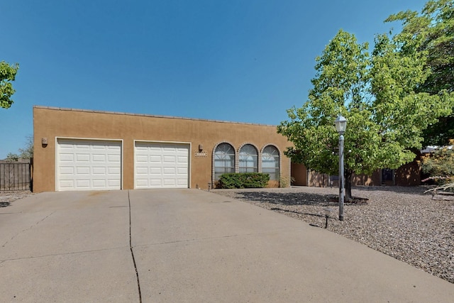 5207 Russell Dr NW, Albuquerque, NM 87114 - pueblo-style home with stucco siding, concrete driveway, and an attached garage