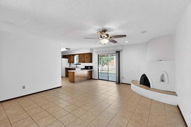 5207 Russell Dr NW, Albuquerque, NM 87114 - unfurnished living room featuring ceiling fan, a textured ceiling, a fireplace with raised hearth, and light tile patterned floors
