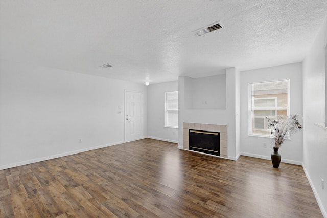 7408 Estes Park Ave NW, Albuquerque, NM 87114 - unfurnished living room with wood finished floors, a tile fireplace, and a textured ceiling