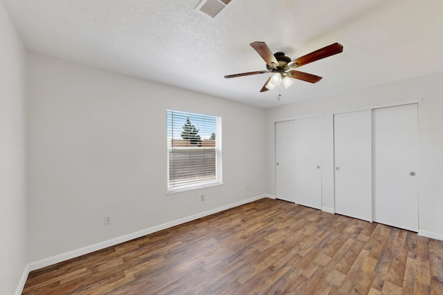 7408 Estes Park Ave NW, Albuquerque, NM 87114 - unfurnished bedroom featuring multiple closets, wood finished floors, a ceiling fan, and a textured ceiling
