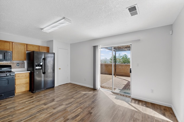 7408 Estes Park Ave NW, Albuquerque, NM 87114 - kitchen featuring black appliances, wood finished floors, light countertops, a textured ceiling, and tasteful backsplash