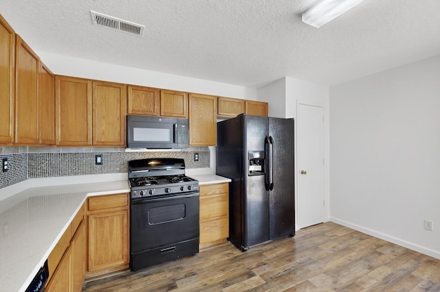7408 Estes Park Ave NW, Albuquerque, NM 87114 - kitchen with black appliances, decorative backsplash, light wood-type flooring, light countertops, and a textured ceiling