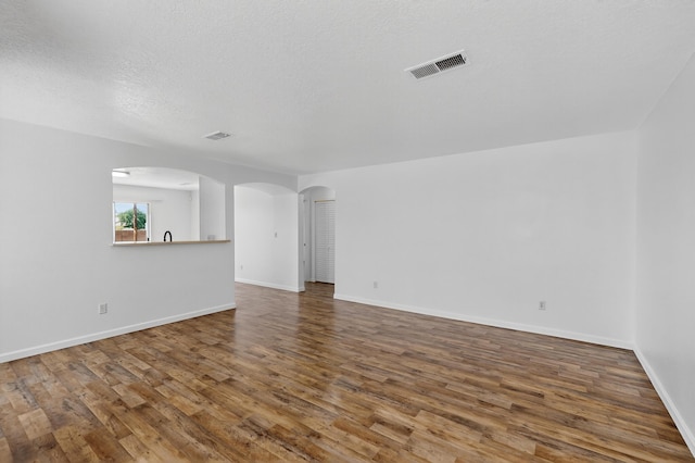 7408 Estes Park Ave NW, Albuquerque, NM 87114 - unfurnished room featuring arched walkways, wood finished floors, and a textured ceiling