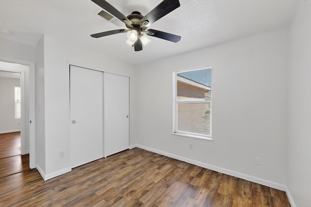 7408 Estes Park Ave NW, Albuquerque, NM 87114 - unfurnished bedroom with multiple windows, wood finished floors, a closet, and a ceiling fan
