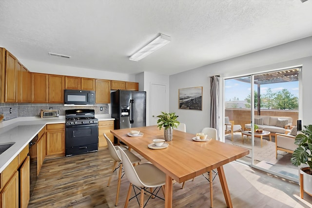 7408 Estes Park Ave NW, Albuquerque, NM 87114 - kitchen featuring black appliances, wood finished floors, light countertops, tasteful backsplash, and a textured ceiling
