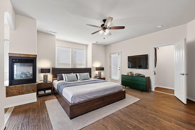 1128 San Augustin Dr, Bernalillo, NM 87004 - bedroom featuring a multi sided fireplace, dark wood-style floors, and a ceiling fan