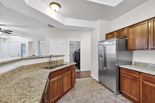 1128 San Augustin Dr, Bernalillo, NM 87004 - kitchen with stainless steel fridge with ice dispenser, washing machine and dryer, ceiling fan, light stone countertops, and brown cabinets
