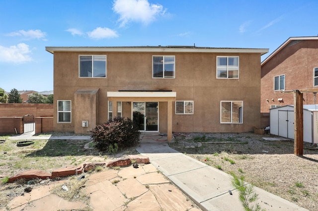 1230 Carrizo St NW, Los Lunas, NM 87031 - rear view of house with a storage shed, stucco siding, and a patio area