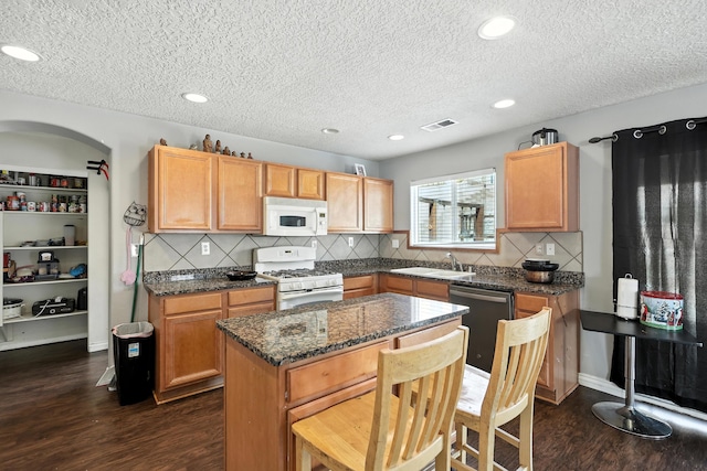 1230 Carrizo St NW, Los Lunas, NM 87031 - kitchen with white appliances, dark wood finished floors, a textured ceiling, decorative backsplash, and a kitchen island