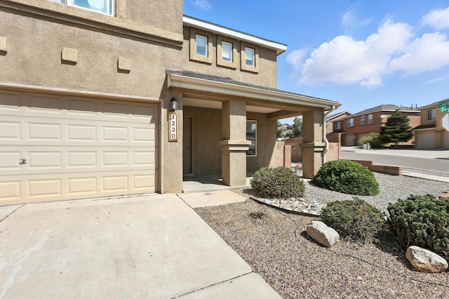1230 Carrizo St NW, Los Lunas, NM 87031 - view of front of home with stucco siding, concrete driveway, covered porch, and an attached garage