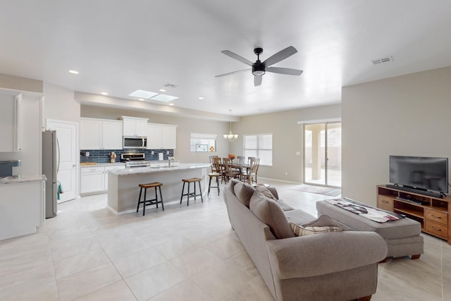 4813 Guadalupe Peak St SW, Los Lunas, NM 87031 - living area featuring a ceiling fan, light tile patterned flooring, recessed lighting, and a chandelier