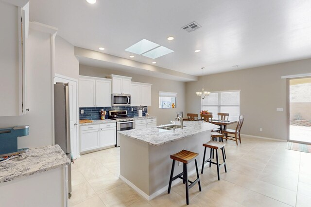 4813 Guadalupe Peak St SW, Los Lunas, NM 87031 - kitchen with stainless steel appliances, white cabinetry, backsplash, a kitchen bar, and recessed lighting