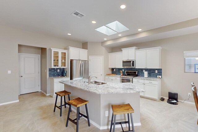 4813 Guadalupe Peak St SW, Los Lunas, NM 87031 - kitchen featuring stainless steel appliances, a skylight, a breakfast bar area, backsplash, and an island with sink