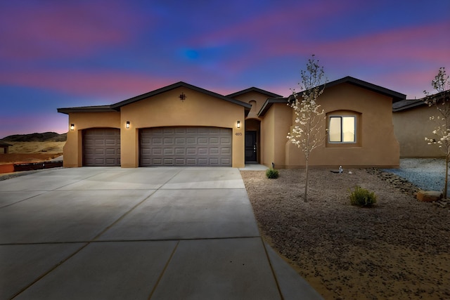 4813 Guadalupe Peak St SW, Los Lunas, NM 87031 - view of front of home with stucco siding, an attached garage, and driveway