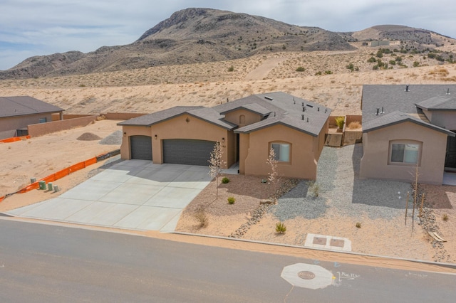 4813 Guadalupe Peak St SW, Los Lunas, NM 87031 - view of front of property with a mountain view, a garage, stucco siding, and concrete driveway