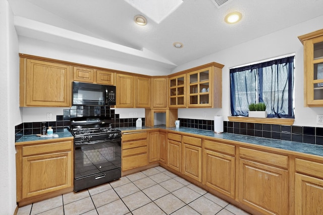 1259 8th St NW, Albuquerque, NM 87102 - kitchen featuring black appliances, vaulted ceiling, light tile patterned flooring, glass insert cabinets, and dark countertops