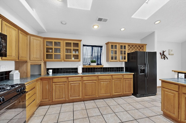 1259 8th St NW, Albuquerque, NM 87102 - kitchen featuring black appliances, glass insert cabinets, dark countertops, a skylight, and brown cabinets