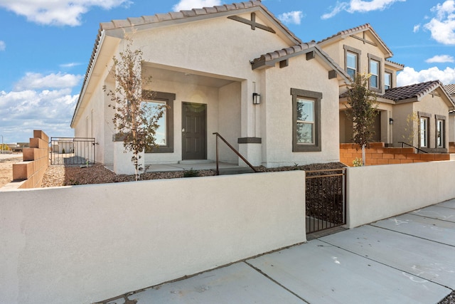 5627 Sagan Loop SE, Albuquerque, NM 87106 - mediterranean / spanish house featuring a gate, a fenced front yard, a tiled roof, and stucco siding