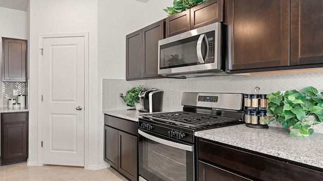 5627 Sagan Loop SE, Albuquerque, NM 87106 - kitchen with stainless steel appliances, dark brown cabinetry, tasteful backsplash, light tile patterned floors, and light stone counters