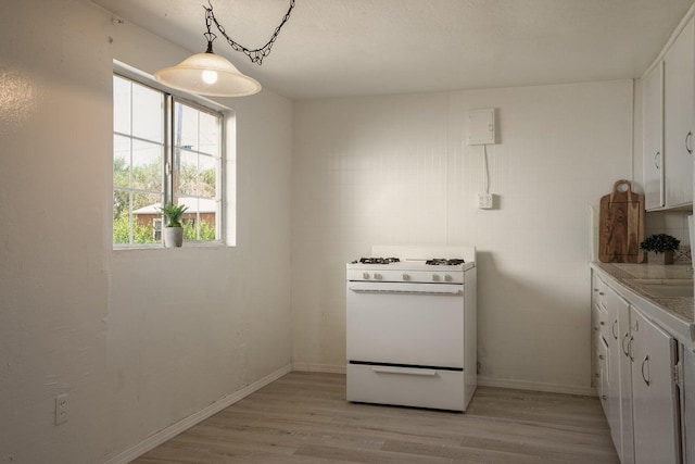 1601 7th St, Moriarty, NM 87035 - kitchen featuring white range with gas cooktop, light wood finished floors, white cabinetry, light countertops, and pendant lighting