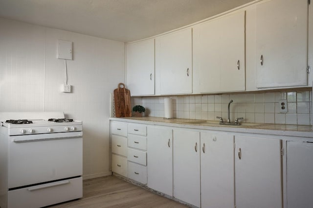 1601 7th St, Moriarty, NM 87035 - kitchen with white range with gas stovetop, light countertops, light wood-style flooring, and white cabinetry