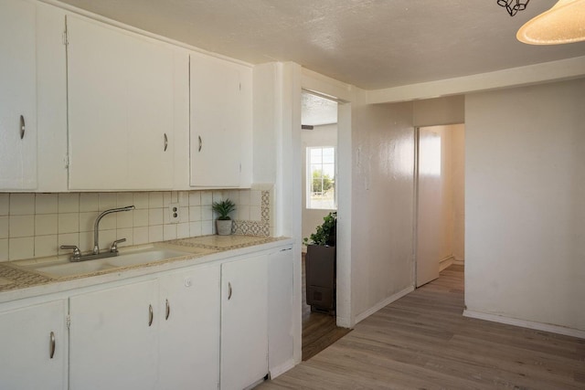 1601 7th St, Moriarty, NM 87035 - kitchen with light wood-type flooring, decorative backsplash, light countertops, and white cabinets