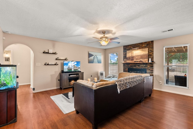 6404 Gambel Quail Rd NE, Rio Rancho, NM 87144 - living area with a fireplace, wood finished floors, a textured ceiling, ceiling fan, and arched walkways