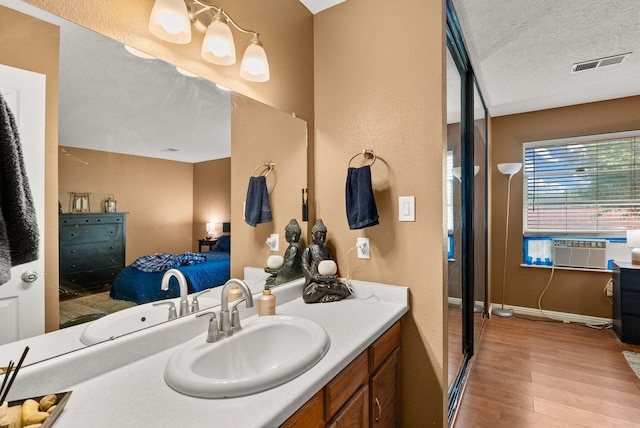 6404 Gambel Quail Rd NE, Rio Rancho, NM 87144 - bathroom with wood finished floors, connected bathroom, vanity, a textured ceiling, and a textured wall