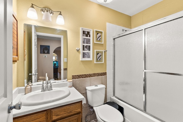 6404 Gambel Quail Rd NE, Rio Rancho, NM 87144 - full bathroom with tile walls, vanity, combined bath / shower with glass door, and a wainscoted wall