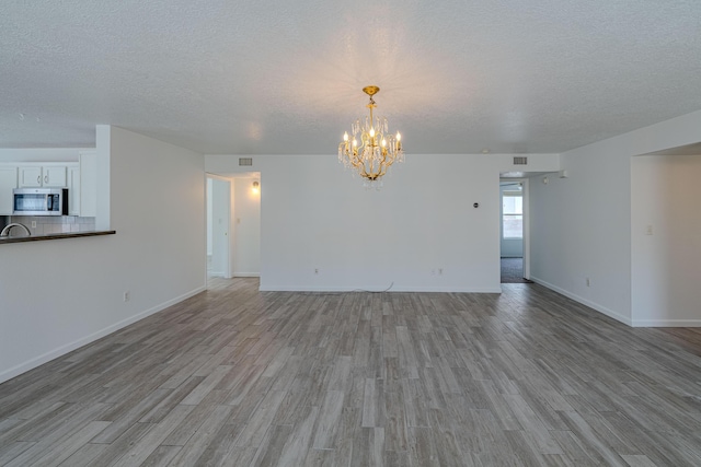 3742 Cattle Dr NE, Rio Rancho, NM 87144 - unfurnished living room with a textured ceiling, light wood-style floors, and a chandelier