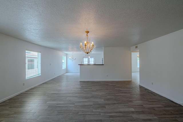 3742 Cattle Dr NE, Rio Rancho, NM 87144 - empty room with a chandelier, a textured ceiling, dark wood finished floors, and plenty of natural light