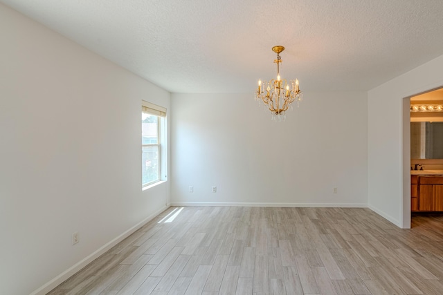 3742 Cattle Dr NE, Rio Rancho, NM 87144 - empty room featuring light wood finished floors, a chandelier, and a textured ceiling