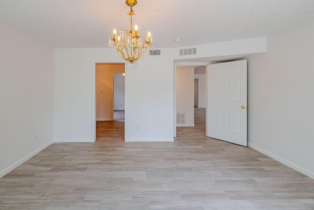 3742 Cattle Dr NE, Rio Rancho, NM 87144 - empty room featuring a chandelier, light wood-type flooring, and a textured ceiling