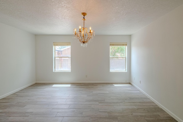 3742 Cattle Dr NE, Rio Rancho, NM 87144 - empty room with a textured ceiling, light wood-style flooring, healthy amount of natural light, and a chandelier