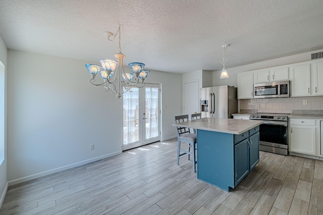 3742 Cattle Dr NE, Rio Rancho, NM 87144 - kitchen with stainless steel appliances, light wood finished floors, light countertops, white cabinetry, and decorative backsplash