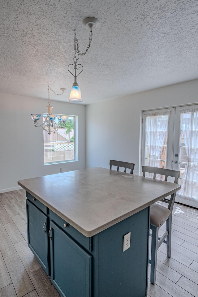 3742 Cattle Dr NE, Rio Rancho, NM 87144 - kitchen featuring wood finish floors, a kitchen bar, a chandelier, blue cabinets, and hanging light fixtures