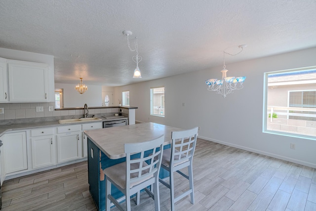3742 Cattle Dr NE, Rio Rancho, NM 87144 - kitchen featuring a chandelier, light wood-type flooring, stainless steel dishwasher, a textured ceiling, and white cabinets