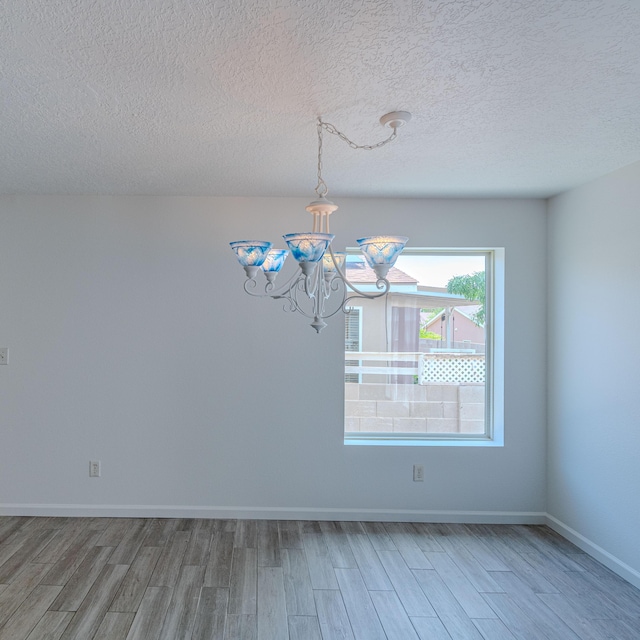 3742 Cattle Dr NE, Rio Rancho, NM 87144 - unfurnished dining area with light wood-style flooring, a chandelier, and a textured ceiling