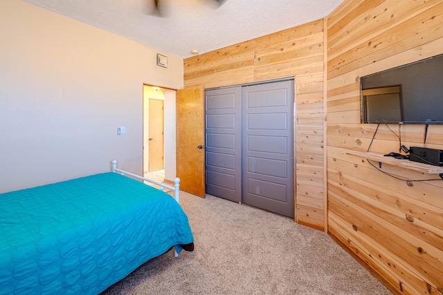 300 Thompson, Moriarty, NM 87035 - bedroom featuring wooden walls, carpet, a closet, and ceiling fan